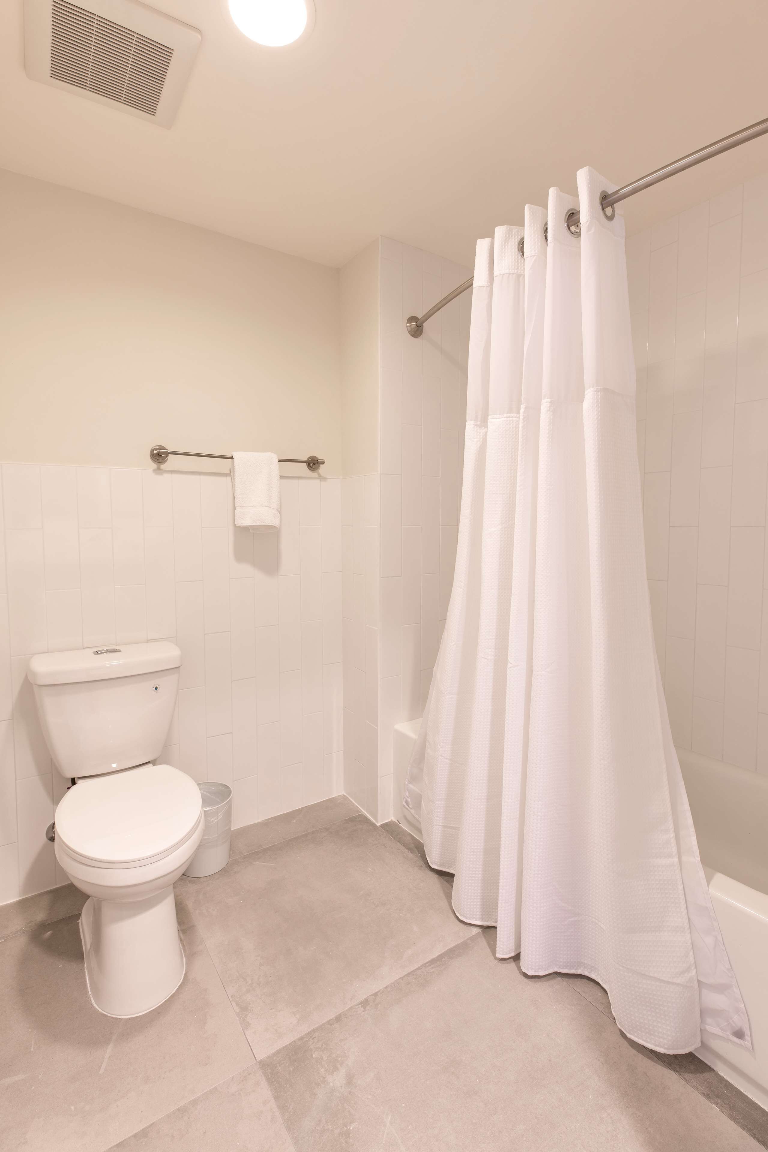 Un baño con inodoro, cortina de ducha y toallero.