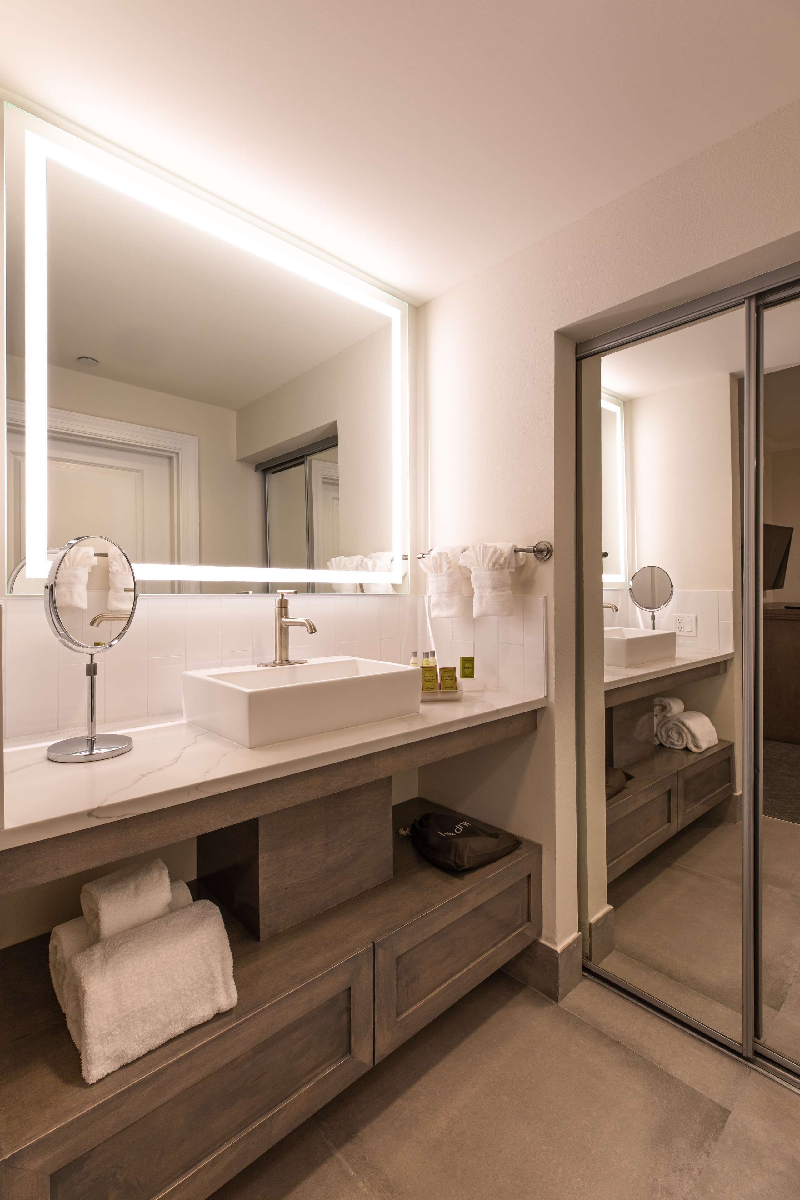 Un bany modern amb un mirall gran, un lavabo i un moble de tocador amb espais d'emmagatzematge.