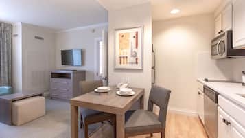 A compact living space with a dining area, kitchenette, and a television mounted on the wall.