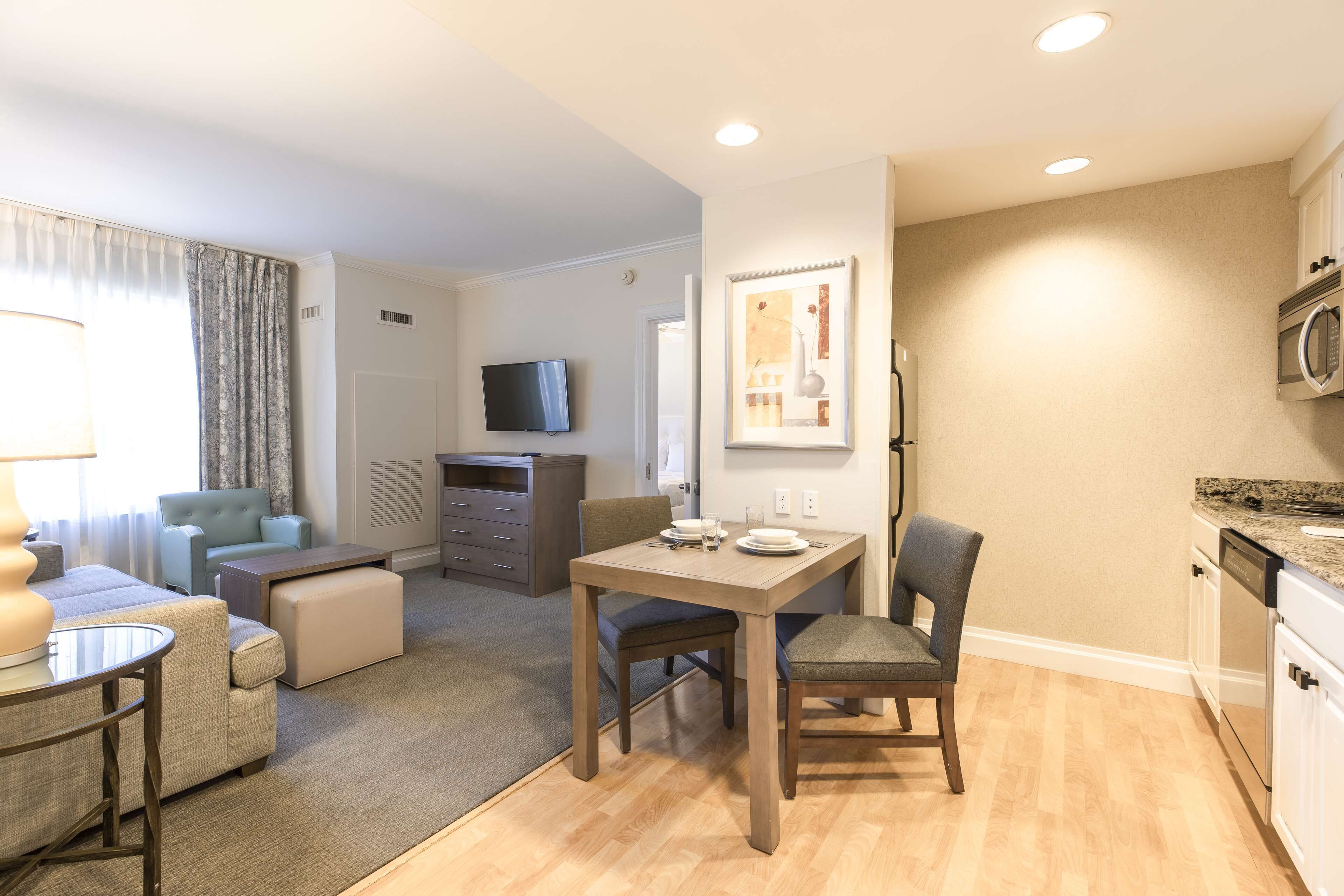 A compact living space with a dining area, kitchenette, and a television mounted on the wall.