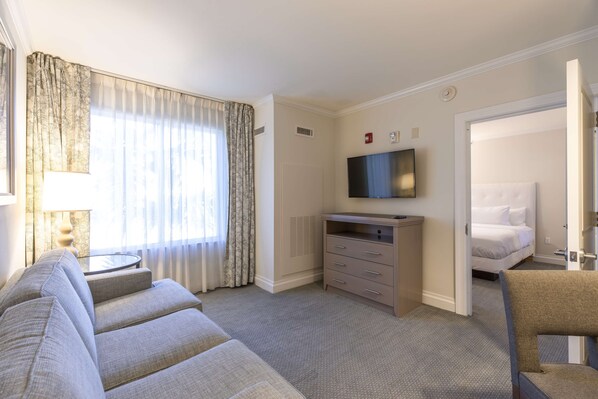 Una habitación de hotel con sofá, televisor, cama y sillón.