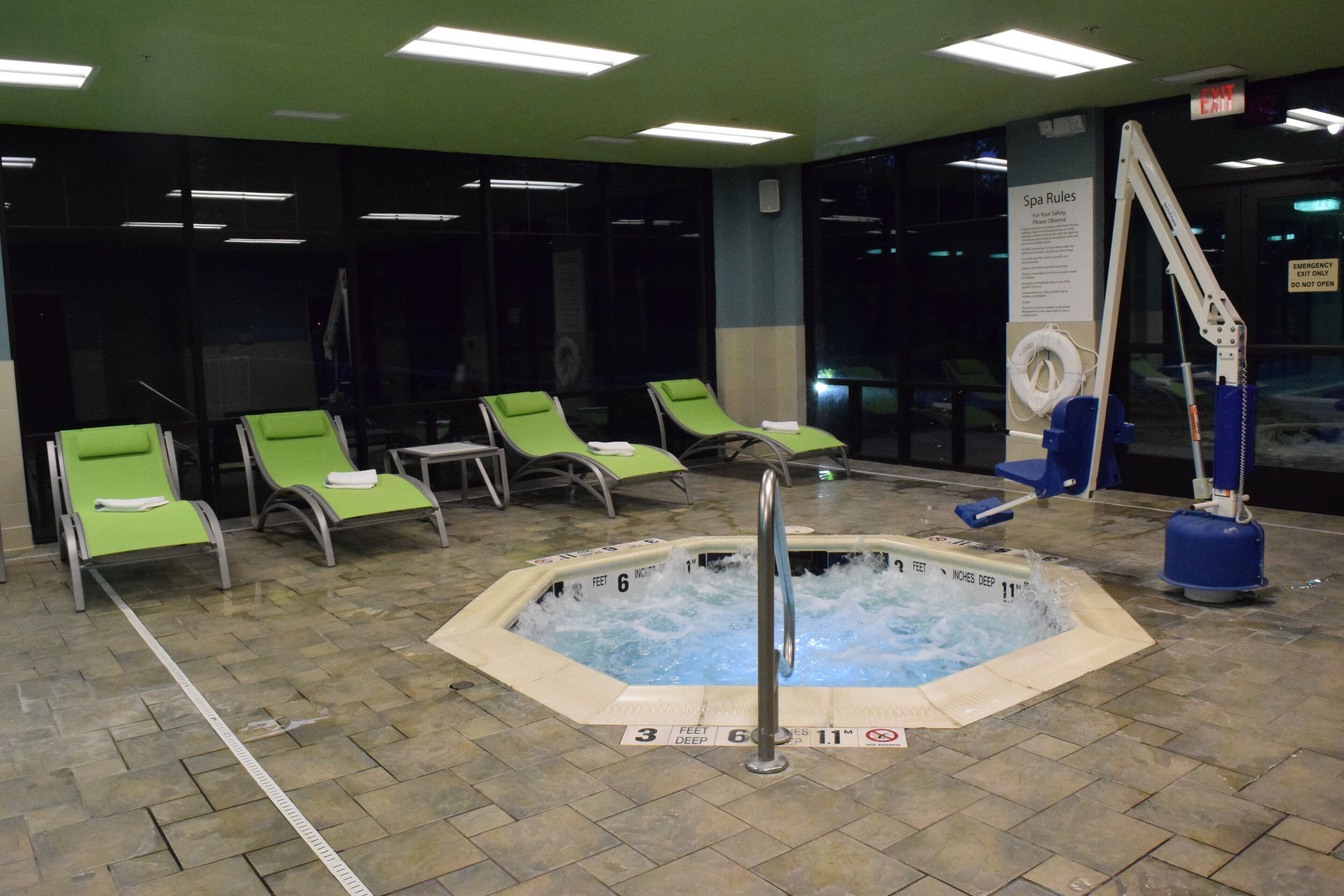 Un área de spa con un jacuzzi, sillones de descanso y una piscina.