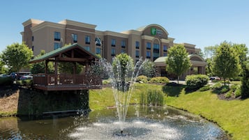 Ein Holiday Inn Express Gebäude mit einem Brunnen und einer hölzernen Terrasse davor.