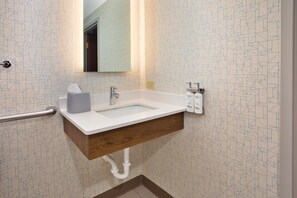 A bathroom with a white sink, wooden vanity, and a mirror.