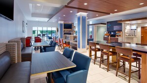 A modern restaurant with high tables and blue chairs, a bar area, and a stone fireplace. - Holiday Inn Express & Suites Rochester Webster by IHG (Webster)