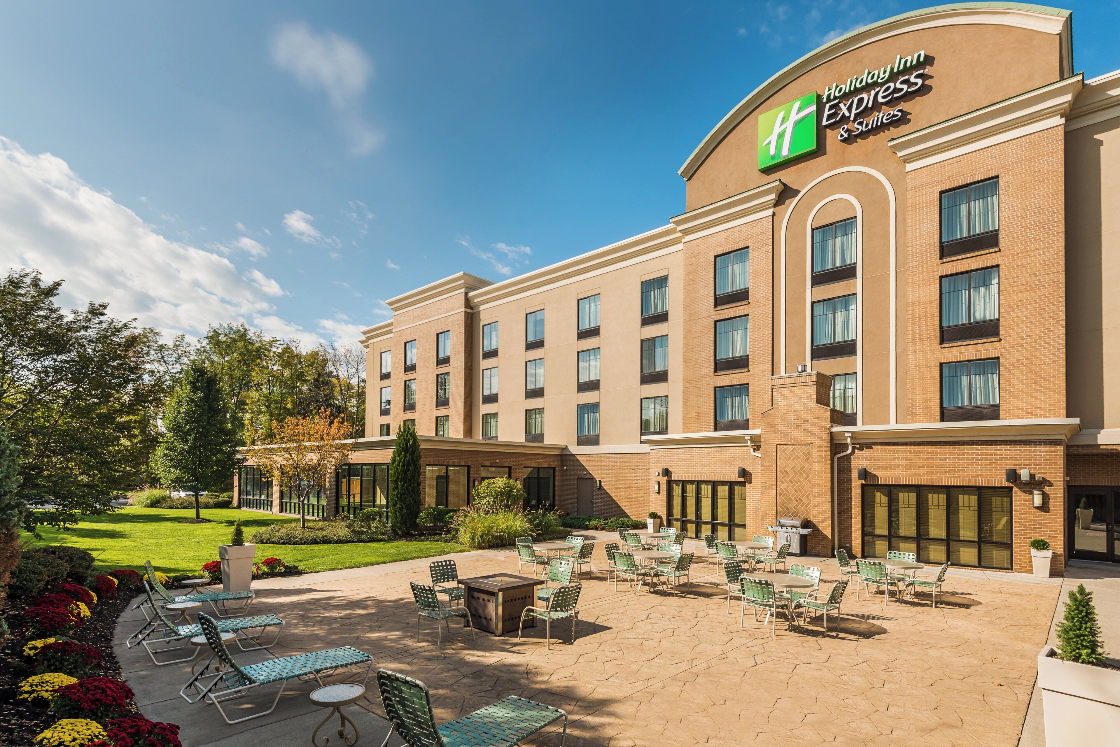 Ein Holiday Inn Express & Suites mit einer Terrasse, die Sitzgelegenheiten und eine Feuerstelle bietet.