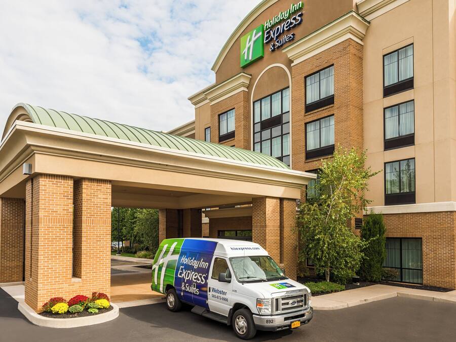 A Holiday Inn Express & Suites building with a covered entrance and a service van parked in front.