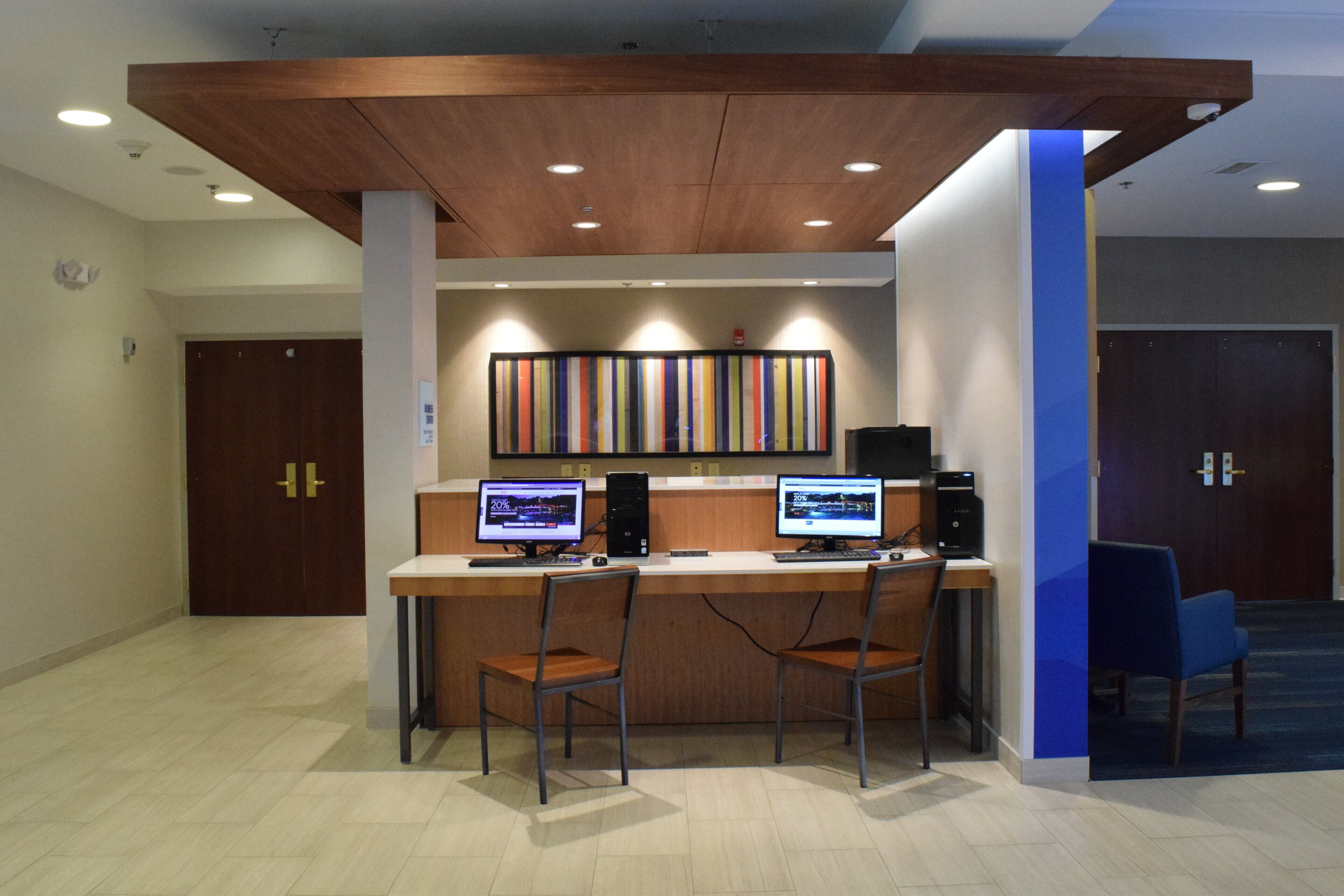 A reception desk with two computer monitors, a telephone, and a keyboard. There are two chairs in front of the desk. The room has a wooden ceiling and a blue accent wall.