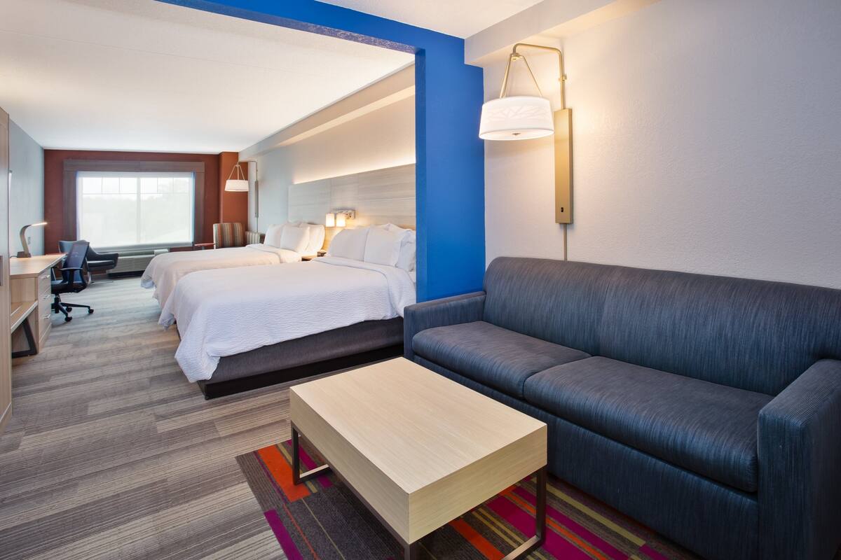 A hotel room with a bed, a sofa, a desk, and a chair.