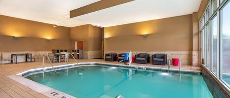 An indoor swimming pool with a 40' no diving depth marker, lounge chairs, and a seating area with tables.