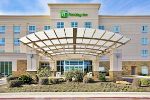 Un hotel Holiday Inn amb entrada coberta, diverses finestres i jardí frontal ben mantingut.