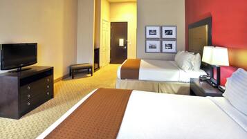 A hotel room with a bed, a television, a desk with a lamp, and a door leading to another room.