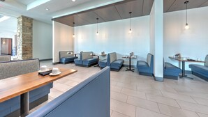 A modern restaurant with high ceilings, recessed lighting, and blue upholstered booths. - Holiday Inn Killeen – Fort Hood Area by IHG (Killeen)