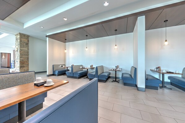 Un restaurante moderno con techos altos, iluminación empotrada y asientos tapizados en tono azul.