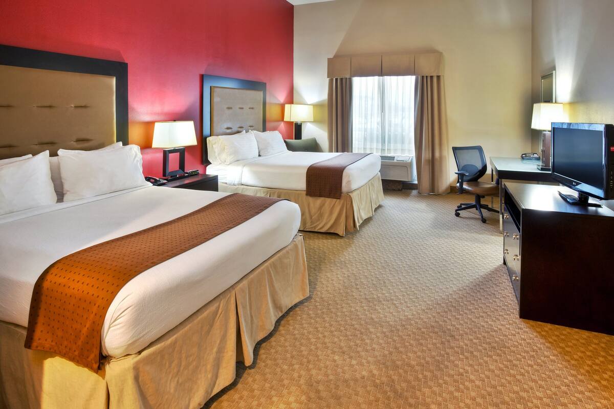 Ein Hotelzimmer mit zwei Betten, einem Schreibtisch mit Computer und einem Fernseher.