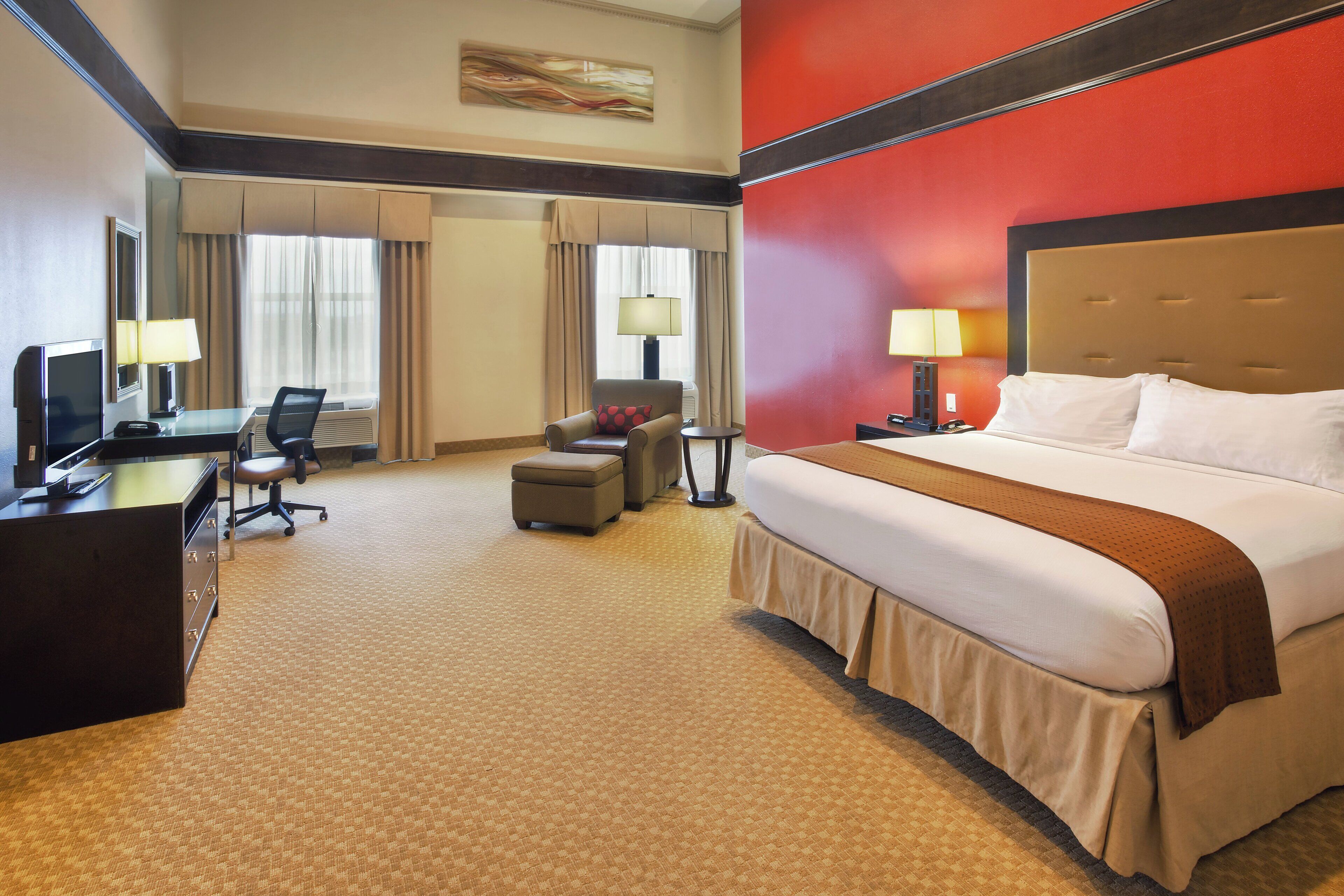 A hotel room with a bed, desk, chair, and a television.