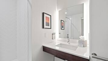 A bathroom with a white sink, a large mirror, and two framed pictures on the wall.