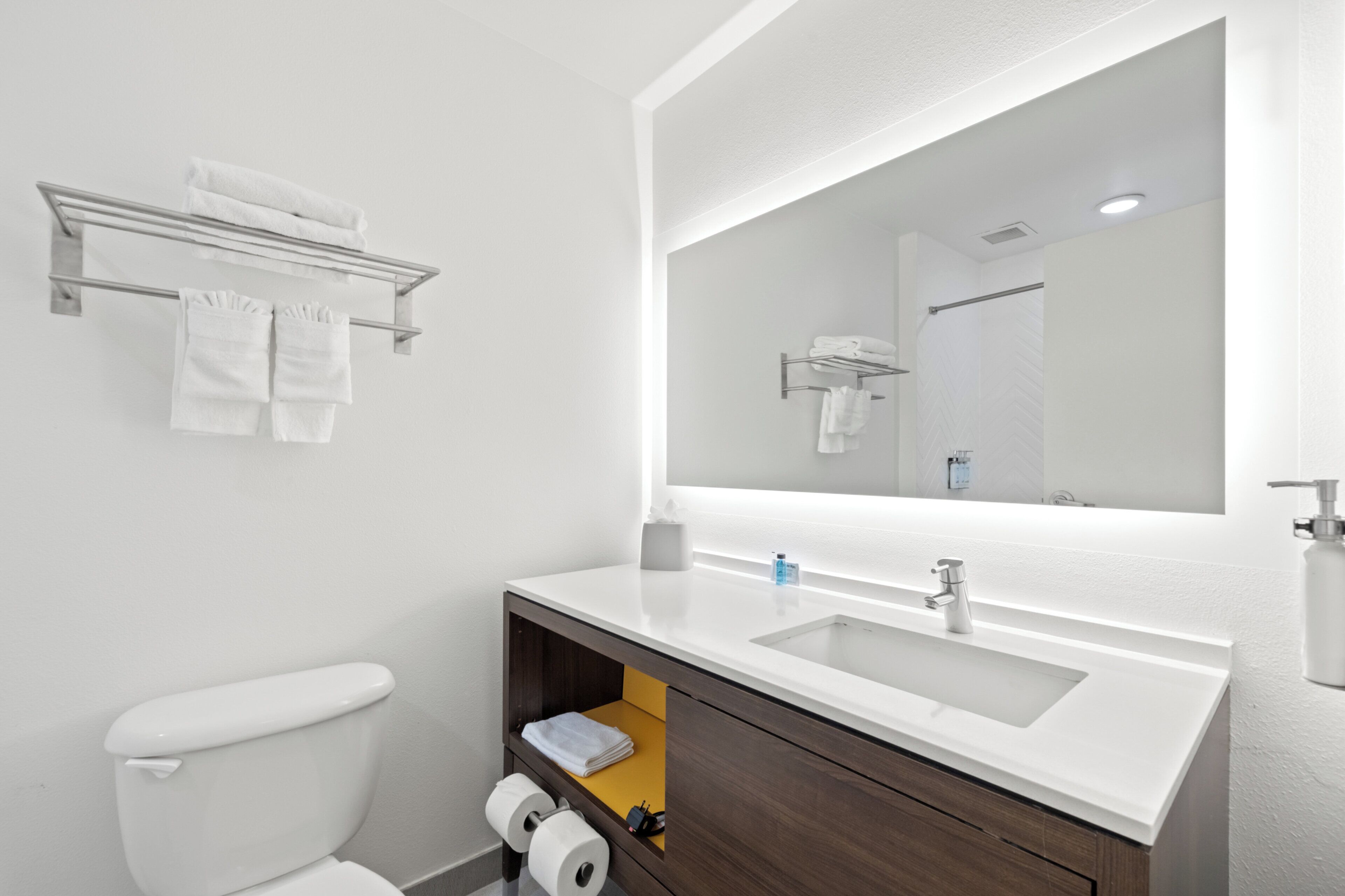 Un baño moderno con un lavamanos blanco, un espejo y un inodoro.