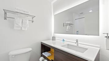 Un baño moderno con un lavamanos blanco, un espejo y un inodoro.