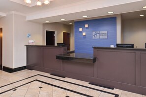 Un hall d’accueil d’hôtel avec un mur bleu, un comptoir de réception et une enseigne indiquant « Holiday Inn Express ».