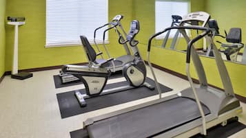 Et fitnessrum med løbebånd, spinningcykel og romaskine.