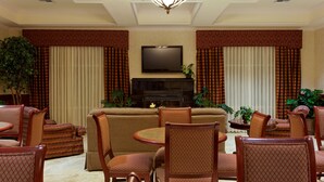 A spacious living room with a large sofa, multiple chairs, a television, and a chandelier.