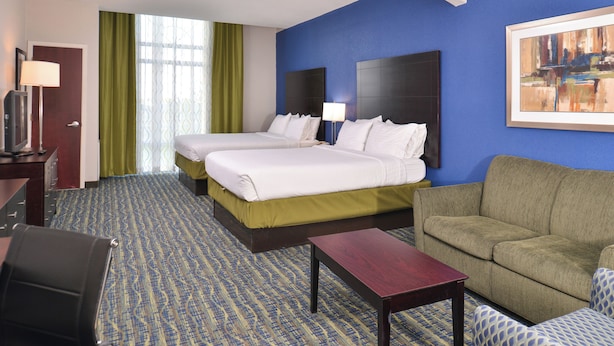 A hotel room with two beds, a sofa, a desk, and a TV. - Holiday Inn Express Hotel & Suites San Antonio by IHG (San Antonio)