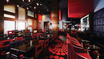 Ein Restaurant mit Sitzgelegenheiten in Boxen und an Tischen, einer Bar und einem gemusterten Boden.