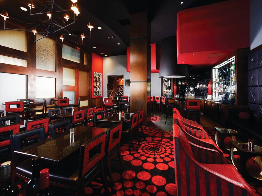 Ein Restaurant mit Sitzgelegenheiten in Boxen und an Tischen, einer Bar und einem gemusterten Boden.