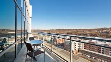 Un balcón con una mesa y sillas, que ofrece vistas a un paisaje urbano con edificios y una carretera.