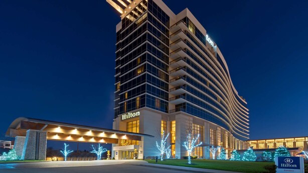 A modern hotel with a curved facade, multiple floors, and illuminated signage.