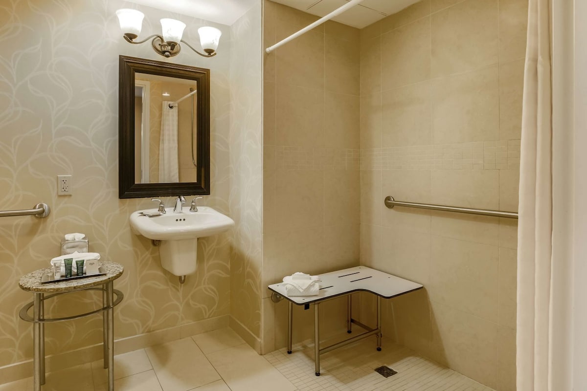 A bathroom with a sink, mirror, towel rack, and a small table with toiletries.