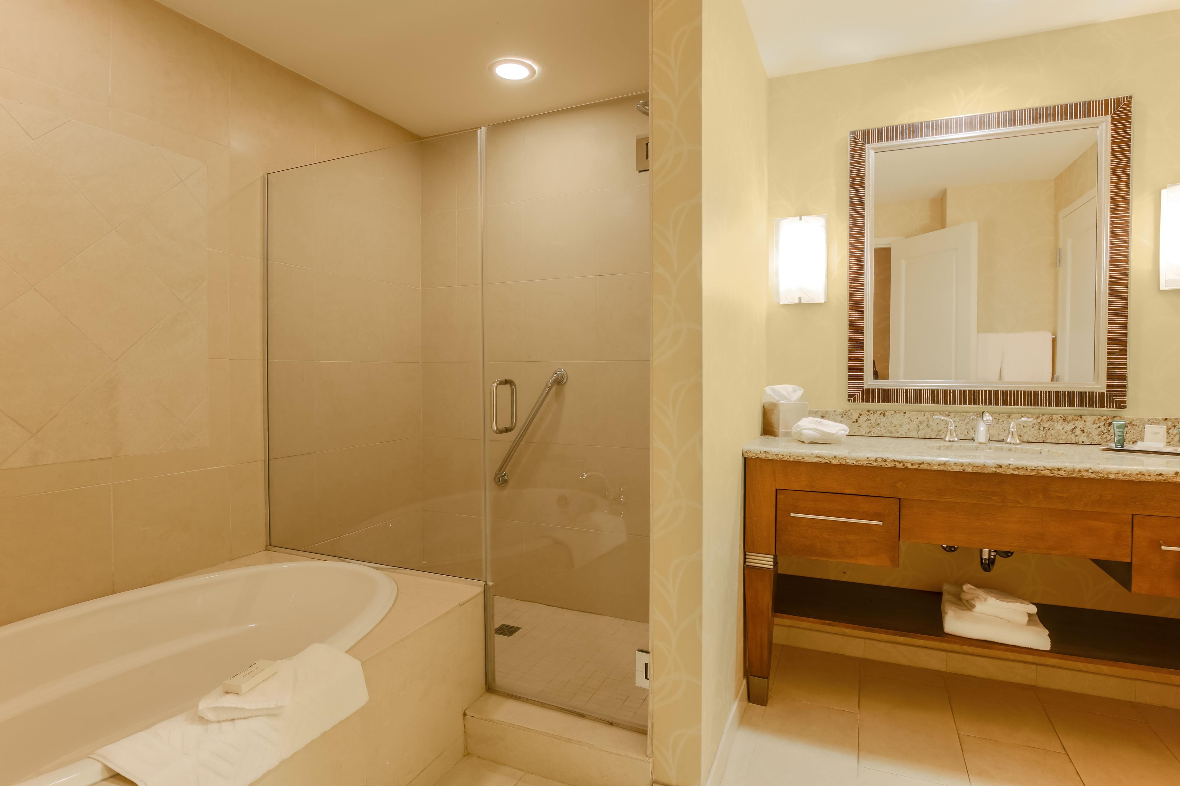 Un baño con bañera, ducha y tocador con espejo.