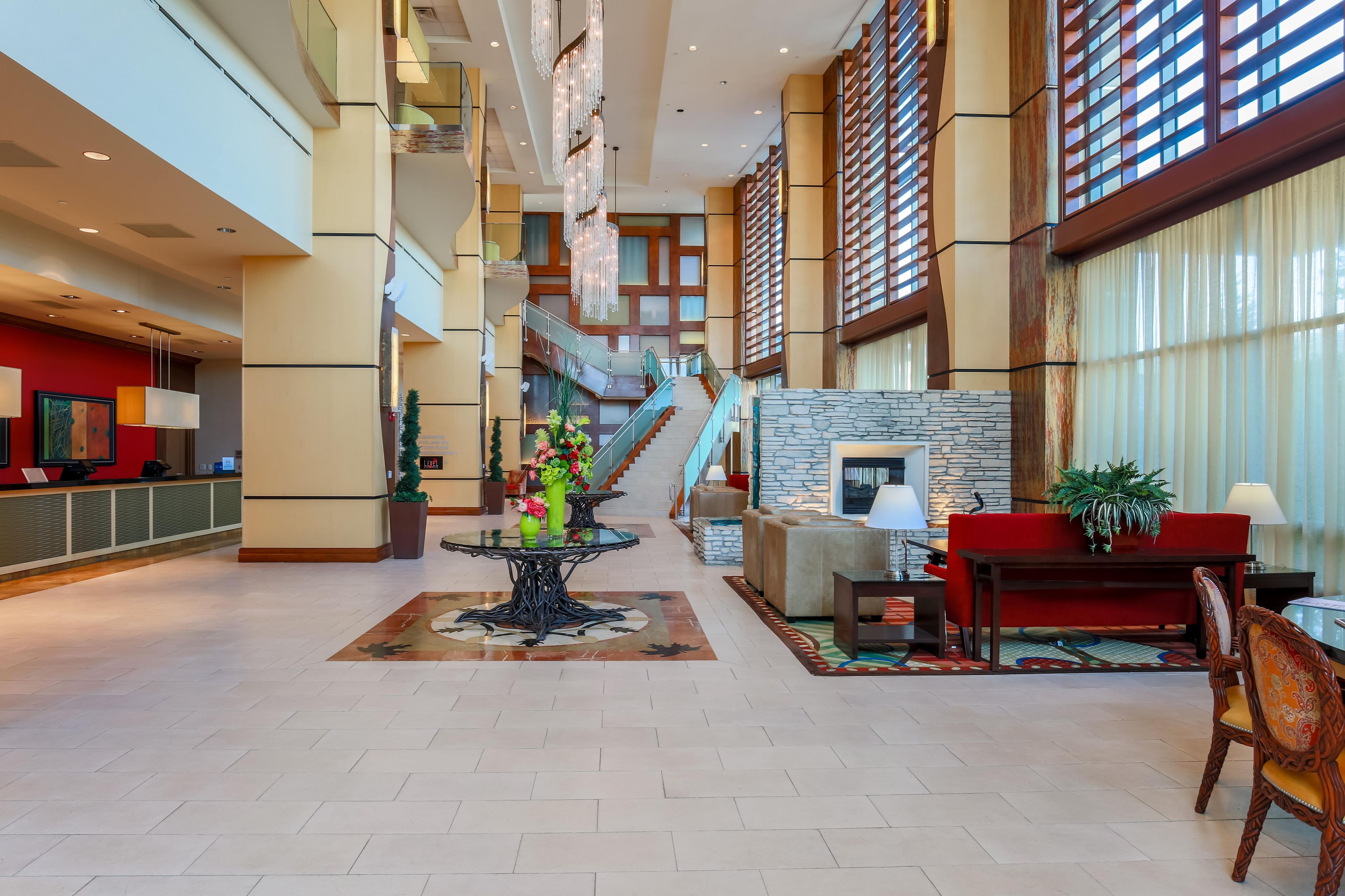 A spacious lobby with a reception desk, a staircase, and a seating area with a fireplace.