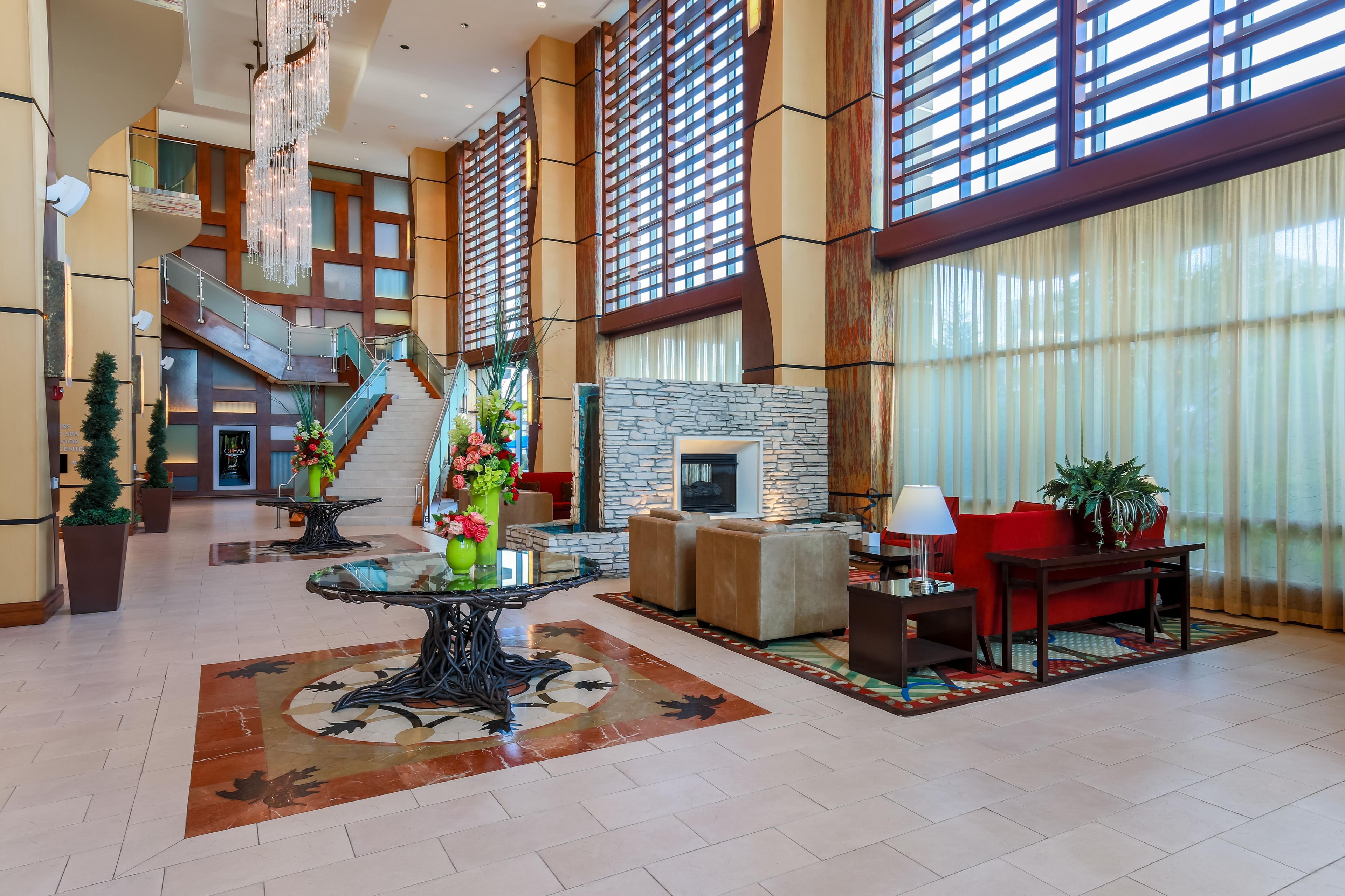 A spacious lobby with a grand staircase, a fireplace, and modern furnishings.