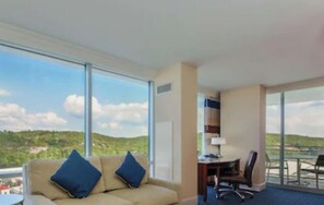 Una habitación de hotel con un ventanal grande, un sofá, un escritorio y una silla.