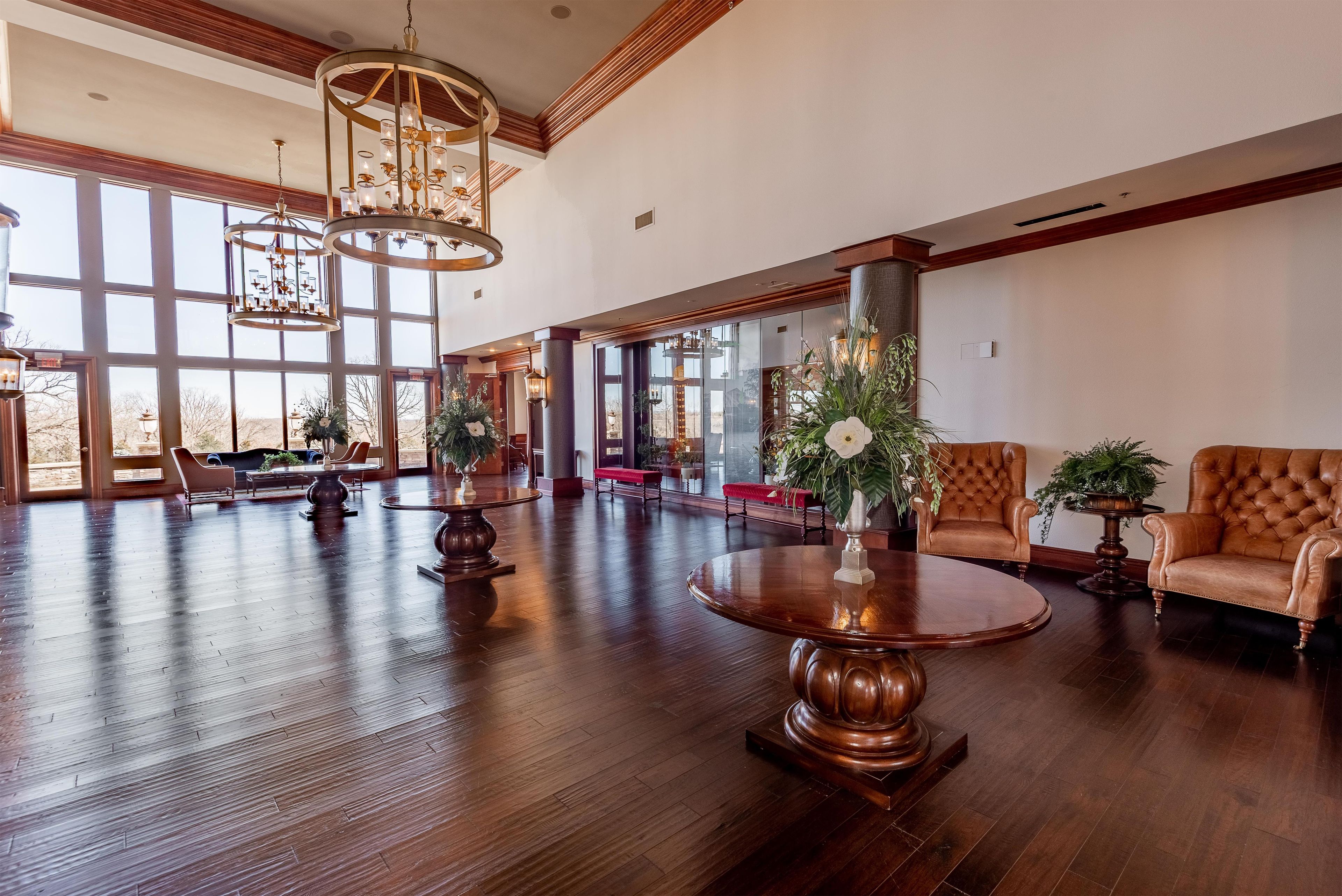A spacious lobby with a high ceiling, large windows, and a grand chandelier.