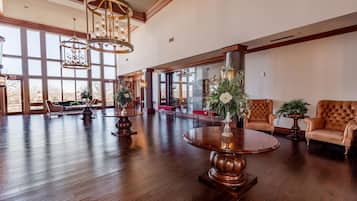 A spacious lobby with a high ceiling, large windows, and a grand chandelier.