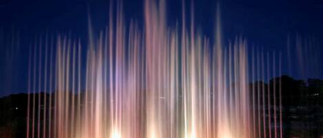 A nighttime fountain display with water jets illuminated in various colors.