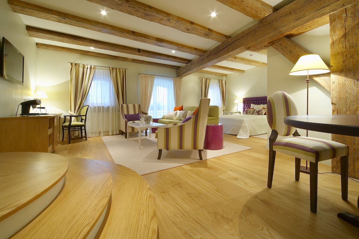 Ein geräumiges Zimmer mit Holzboden, einem Bett, einem Esstisch und einer Couch.