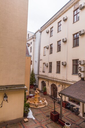 A courtyard with a fountain, outdoor seating, and a building with multiple windows and air conditioning units. - Garden Palace Hotel (Riga)