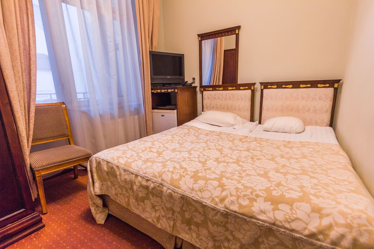 Ein Hotelzimmer mit Bett, Fernseher, Sessel und Schreibtisch.