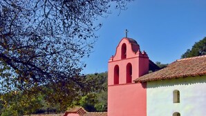A pink church with a bell tower and a white building with arched windows. - Lotus of Lompoc - A Great Hospitality Inn (Lompoc)