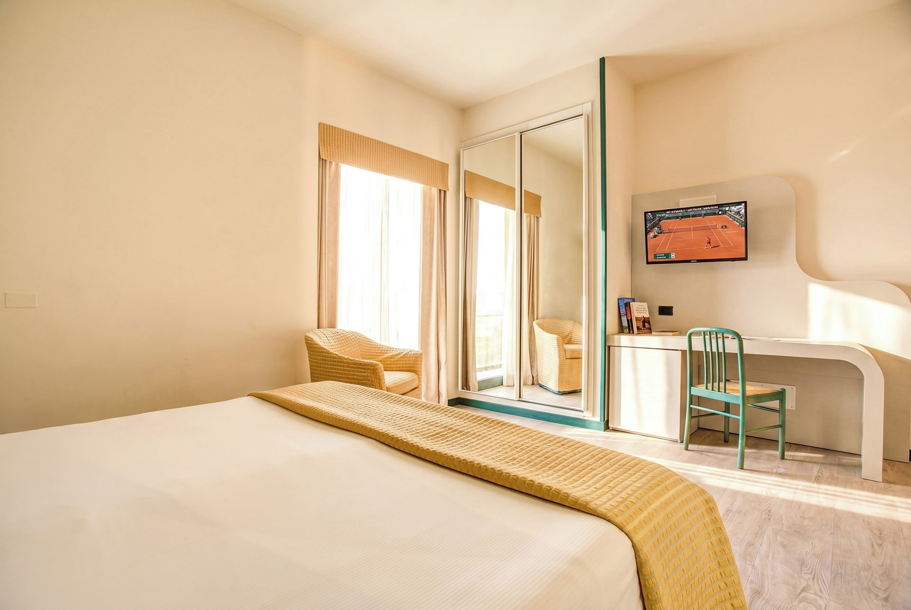 Habitación de hotel con cama, escritorio, silla y televisor.