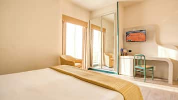 Habitación de hotel con cama, escritorio, silla y televisor.
