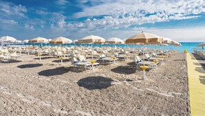 A beach with rows of sun loungers and umbrellas, a clear sky, and a pool area. - Hotel Le Palme (Cervia)