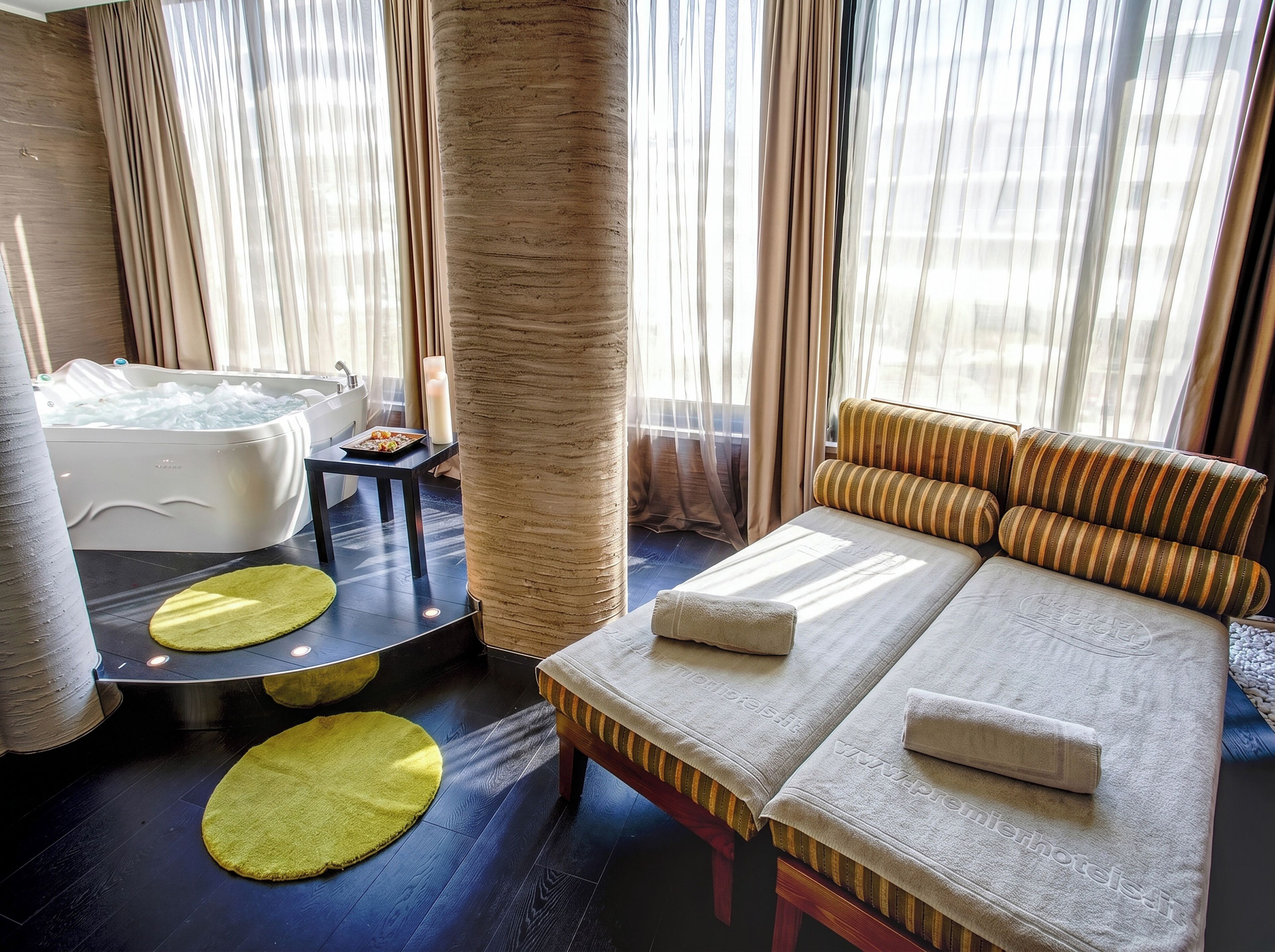 Un cuarto de spa con una camilla de masaje, una bañera y un ventanal grande con cortinas.