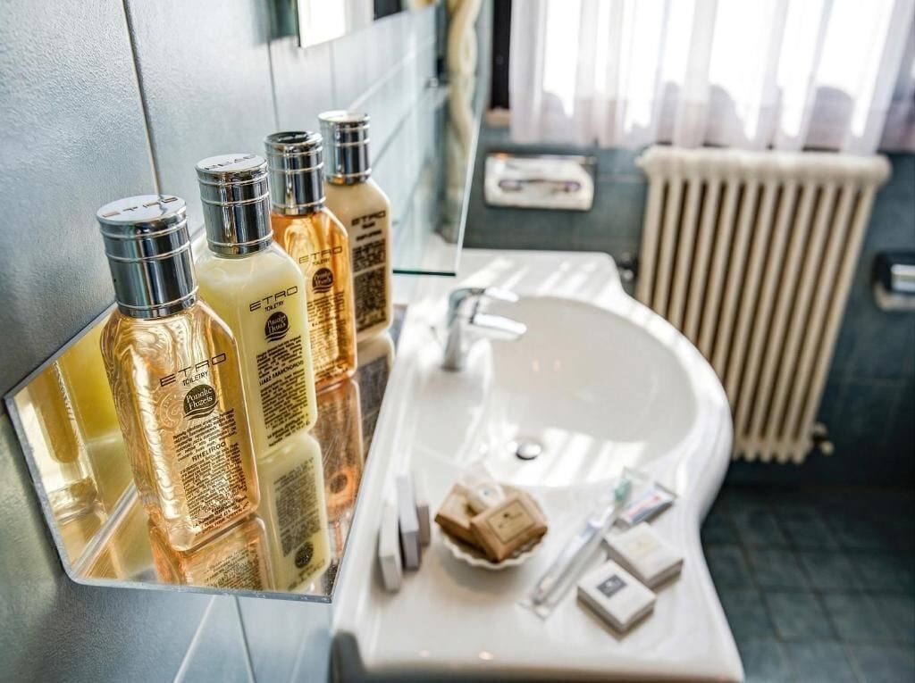 A bathroom with a mirror, sink, toiletries, and a radiator.