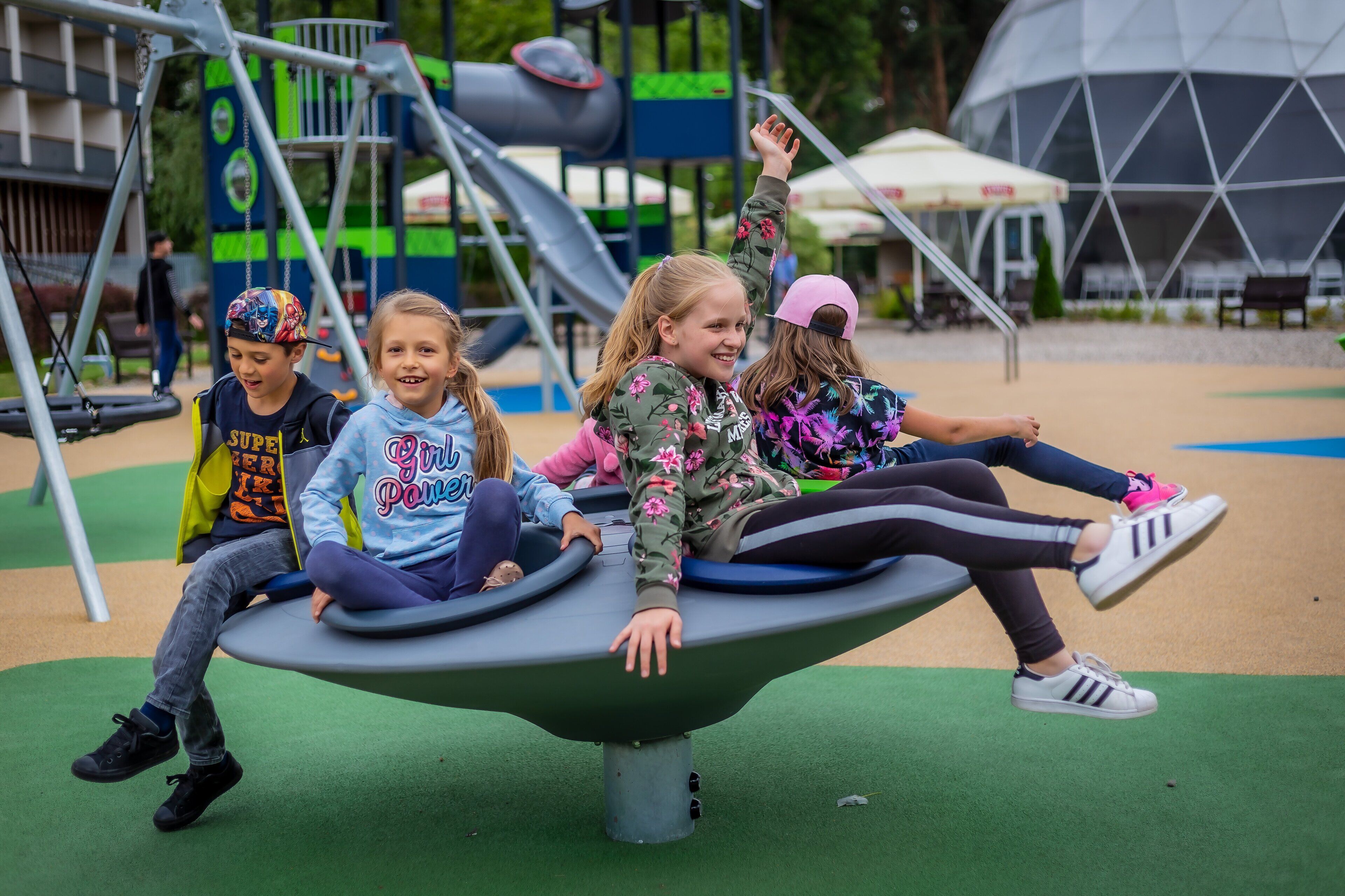 Children playing on a playground with a slide and climbing structures.