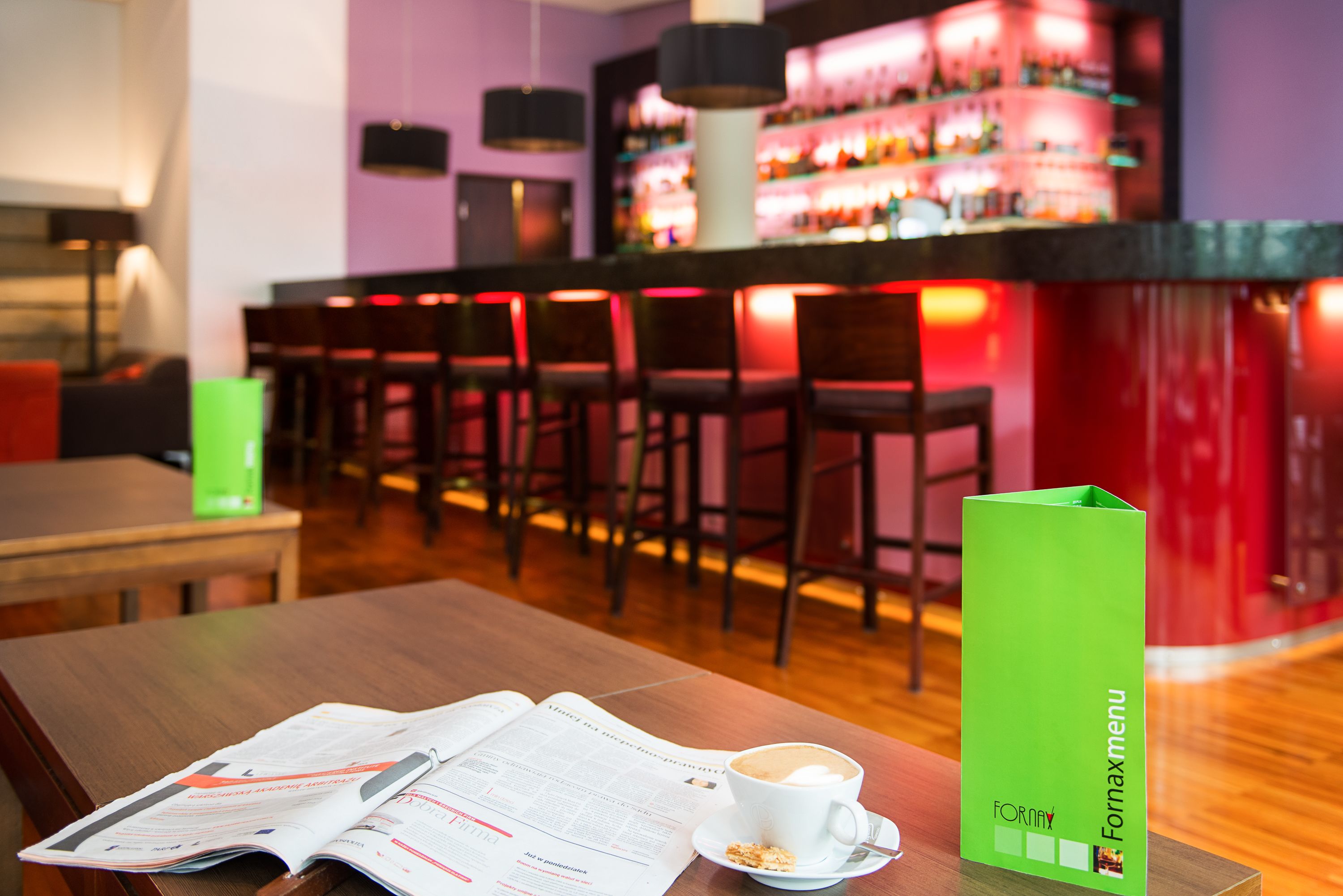 Et barområde med en menustand, et bord med menu og en kop kaffe.